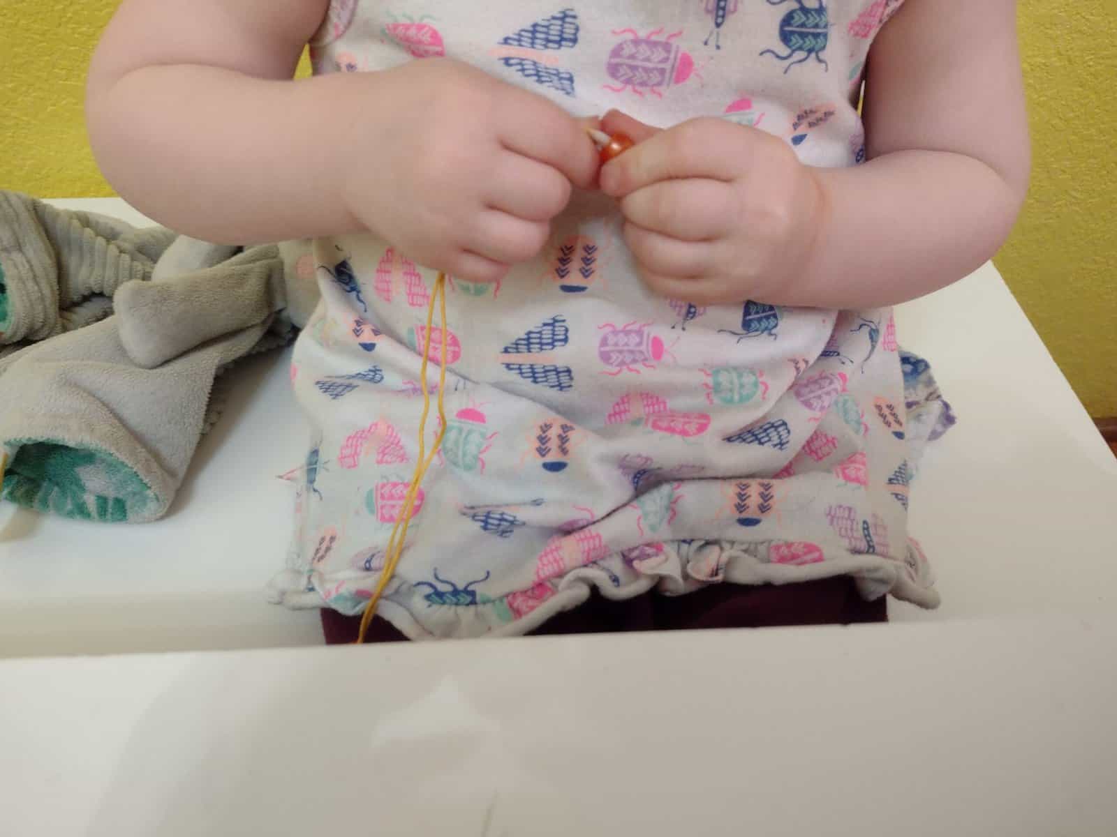 Picture of toddler string beads onto string