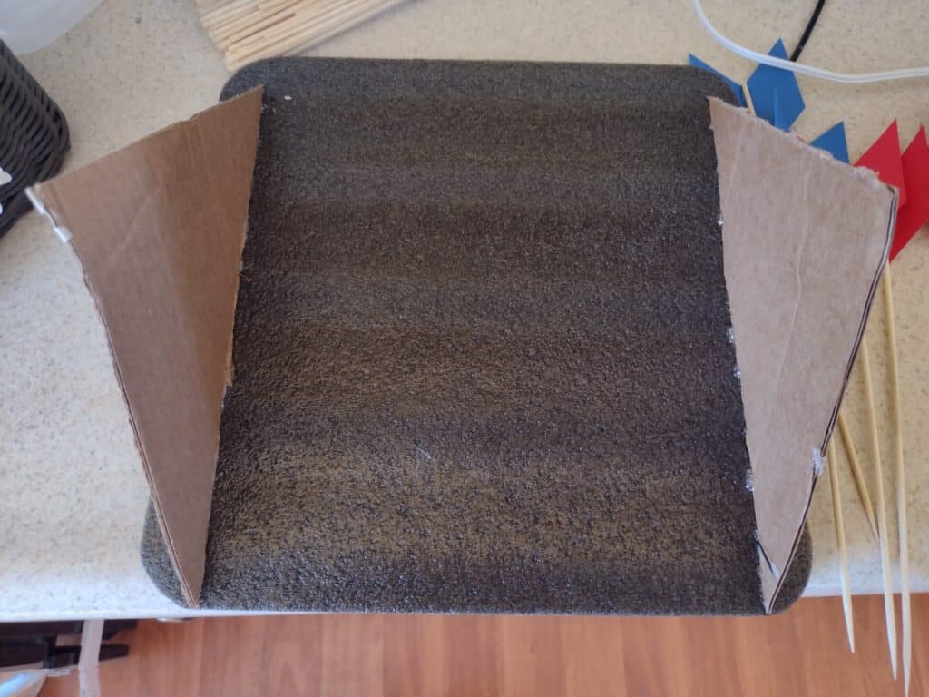 Picture of two triangle shaped pieces of cardboard glued to the back of a sheet of foam