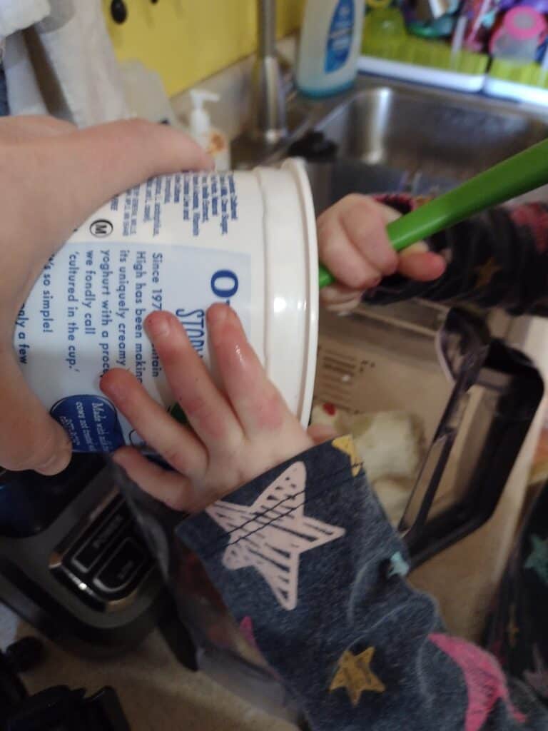 Picture of a preschooler using a spatula to get yogurt into a blender