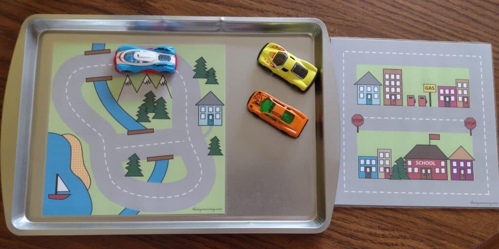 Picture of matchbox cars and a road map held on by magnets to a cookie sheet with another road map off to the side