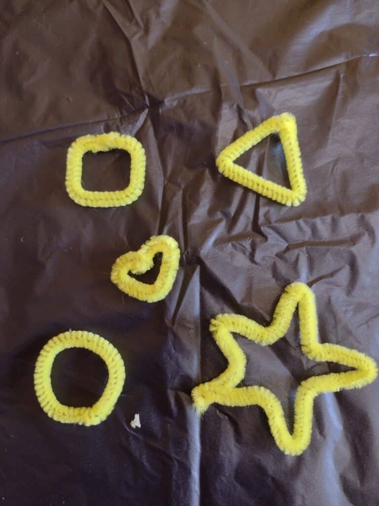 Picture of yellow pipe cleaners twisted into a square, triangle, heart, star, and circle