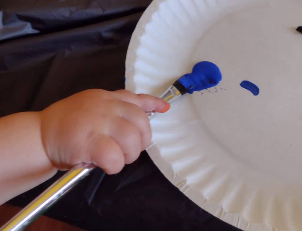 Picture of a toddler getting blue paint on his brush