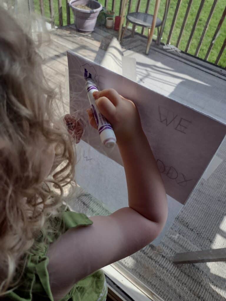 Picture of a preschooler tracing letters with a purple marker