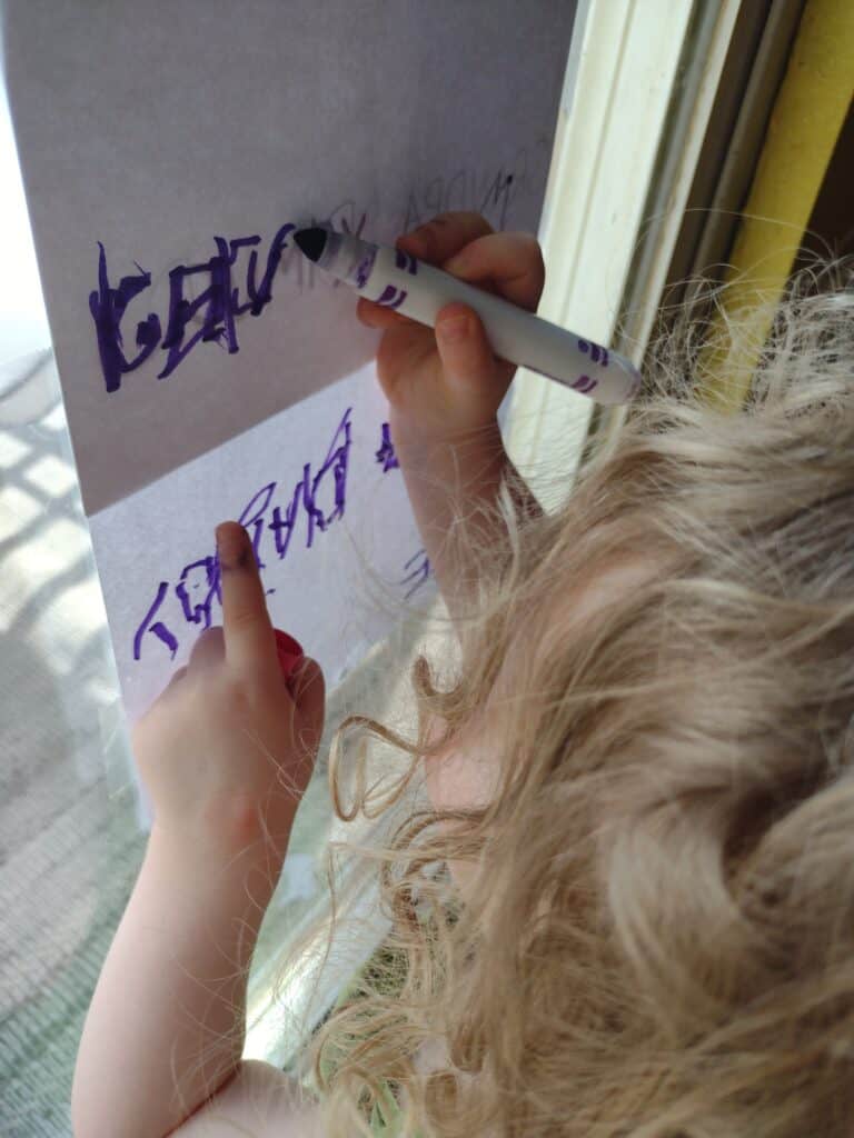 Picture of a preschooler tracing letters with a purple marker