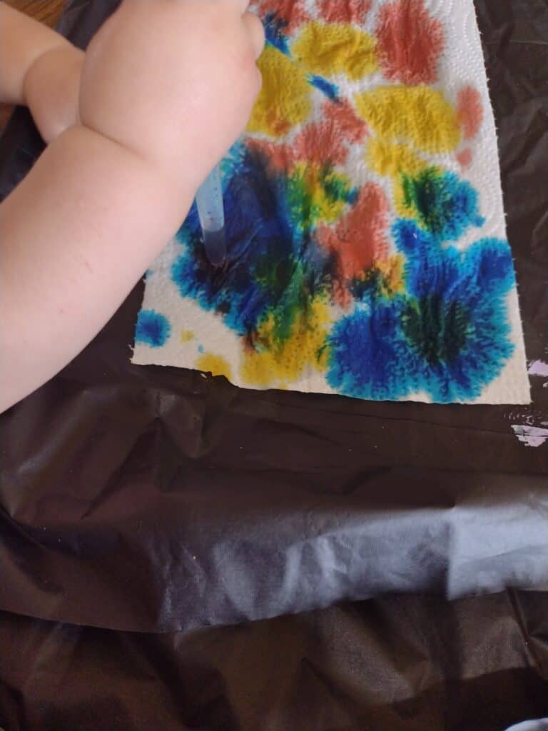 Picture of a toddler dropping food dye on a paper towel