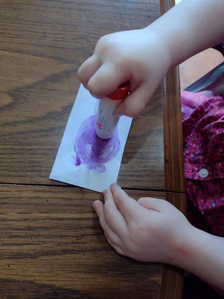 Picture of a preschooler using a glue stick on the back of a strip of paper