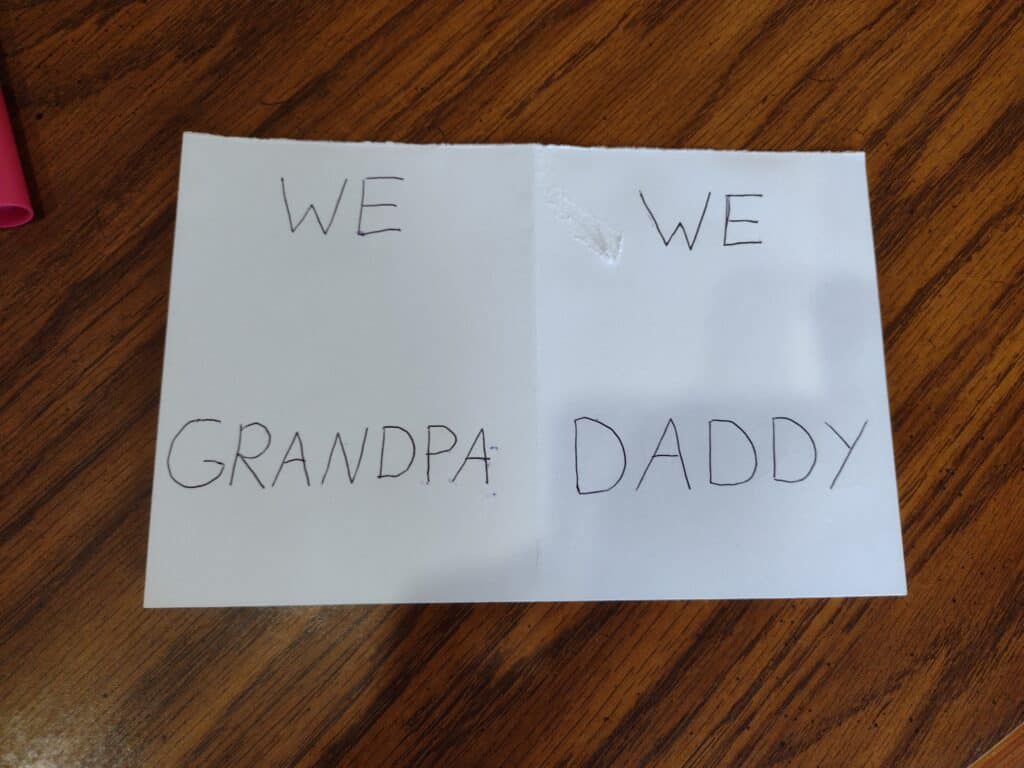 Picture of a piece of cardstock with "We Grandpa" and "We Daddy" written on it