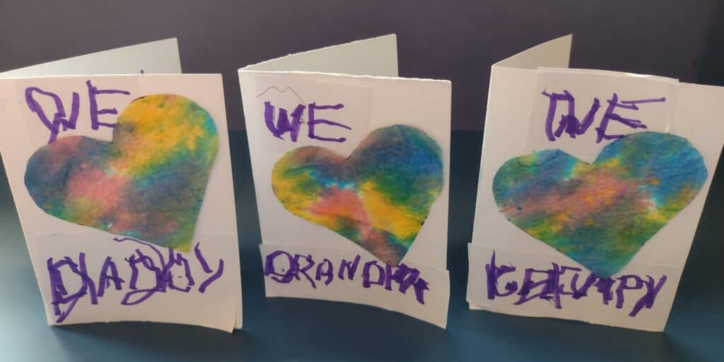 Picture of homemade Father's day cards that say "We love Daddy" "We love Grandpa" and "We love Grumpy". The love is a heart made from tie dye paper towel.