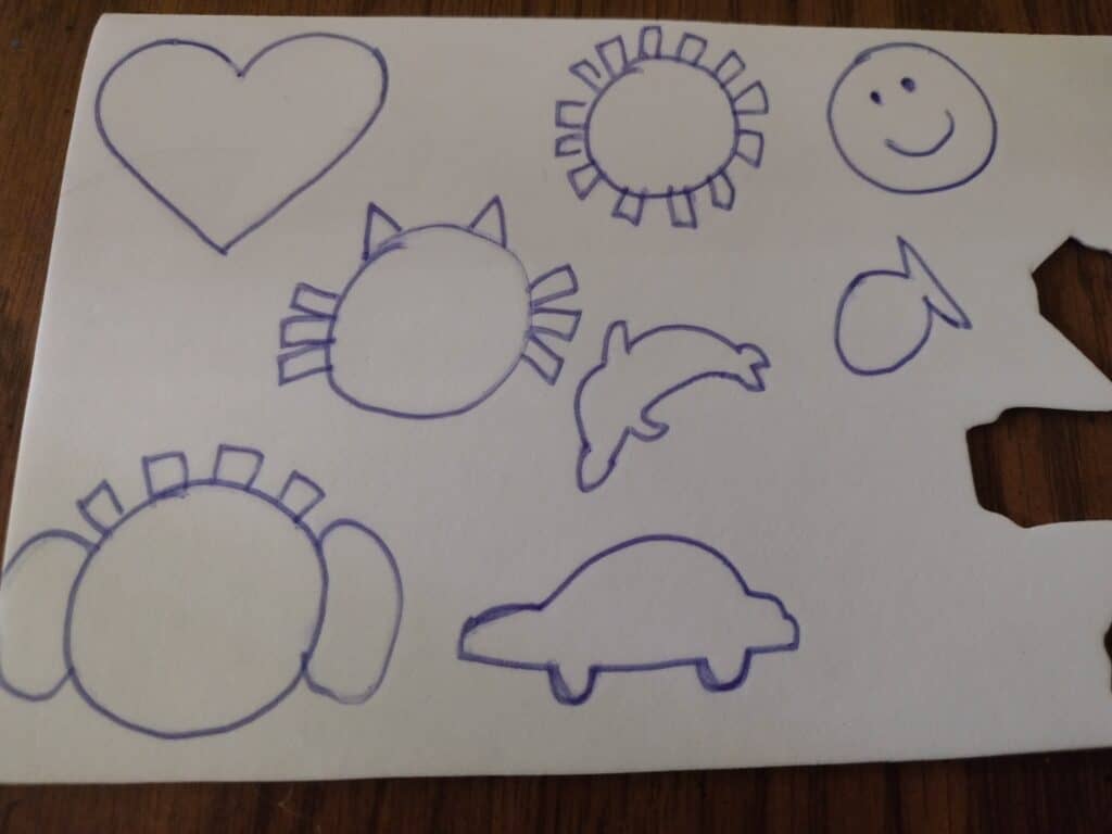 Picture of heart, sun, smiley face, cat, dolphin, fish, elephant lovey, and car drawn on a white foam sheet
