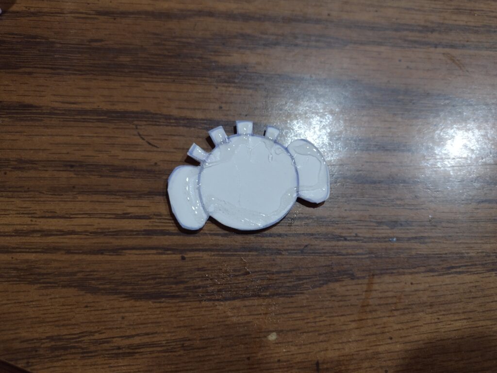 Picture of a piece of white foam cut into a shape of an elephant lovey with hot glue on top