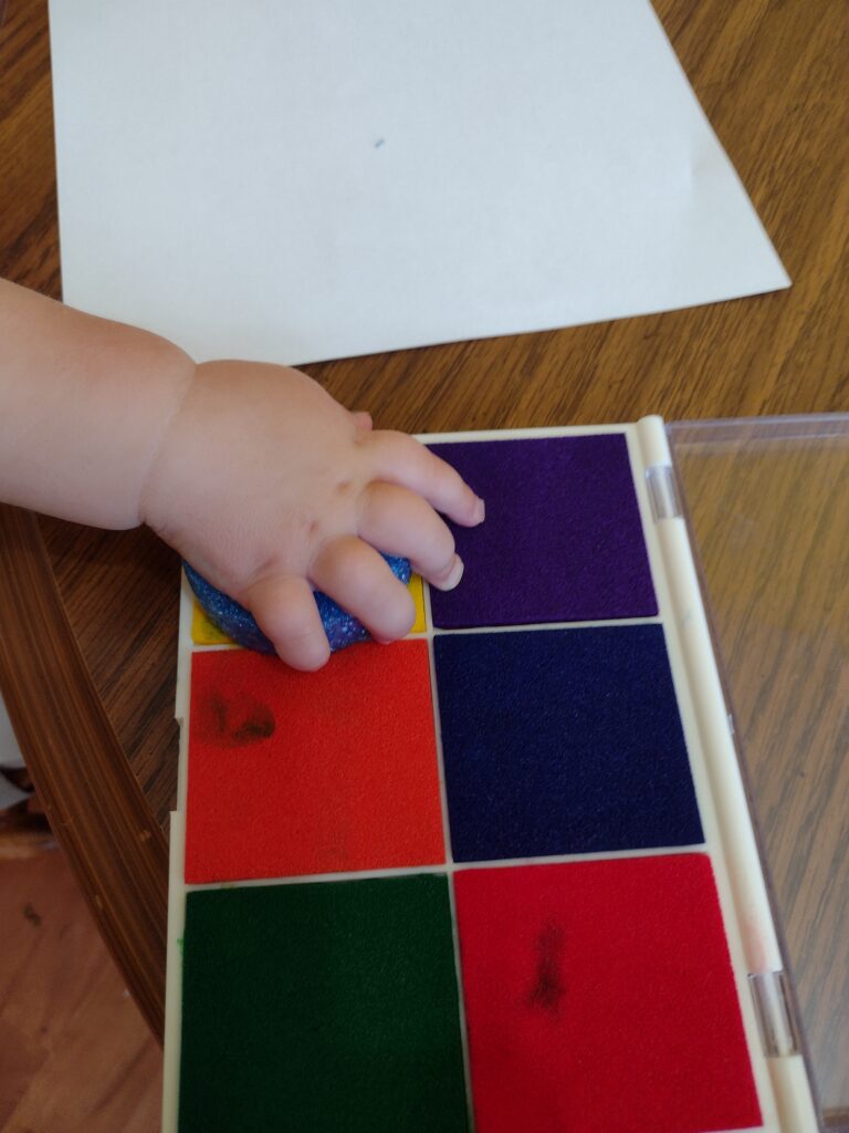 Picture of toddler pressing a handmade stamp onto an ink pad