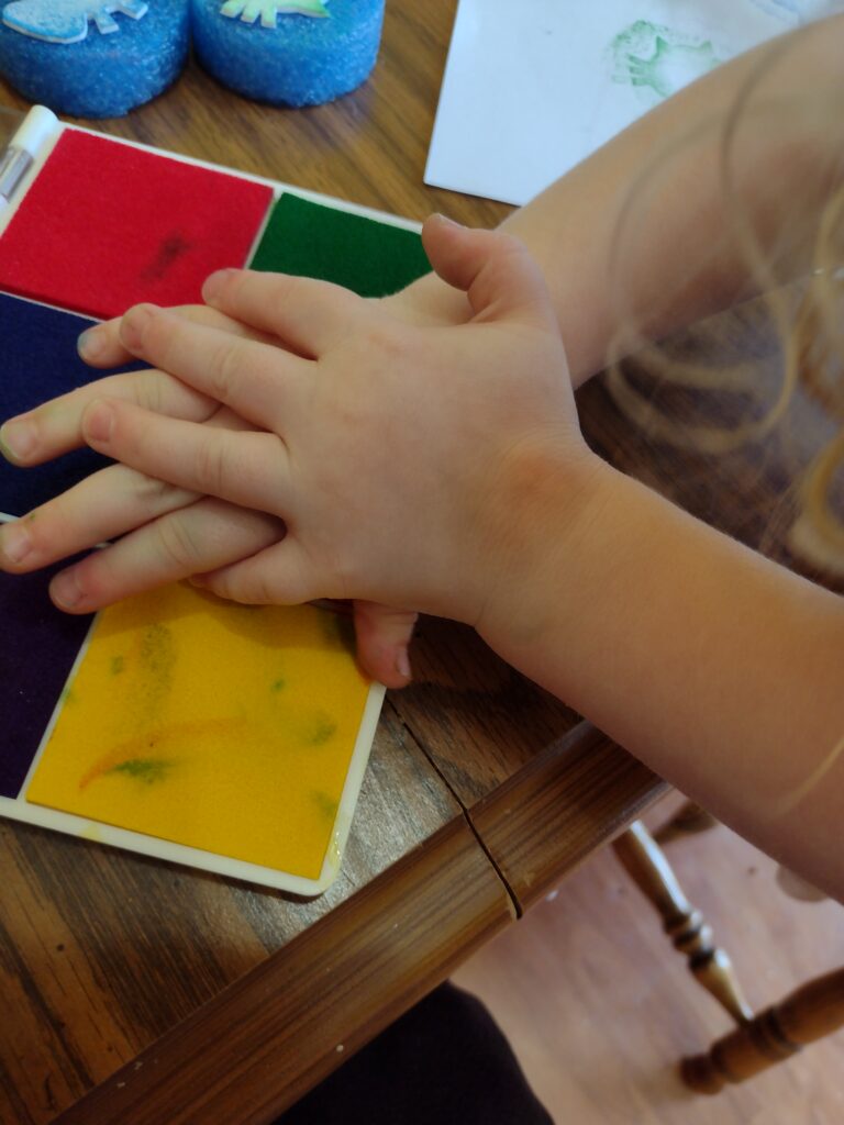 Picture of a preschooler pressing a handmade stamp down on an ink pad