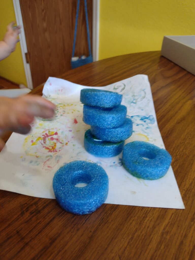 Picture of a toddler stacking handmade stamps made from pool noodles