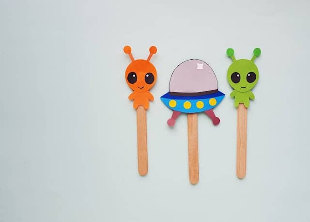 Pictures of aliens and a ufo glued to the end of popsicle sticks