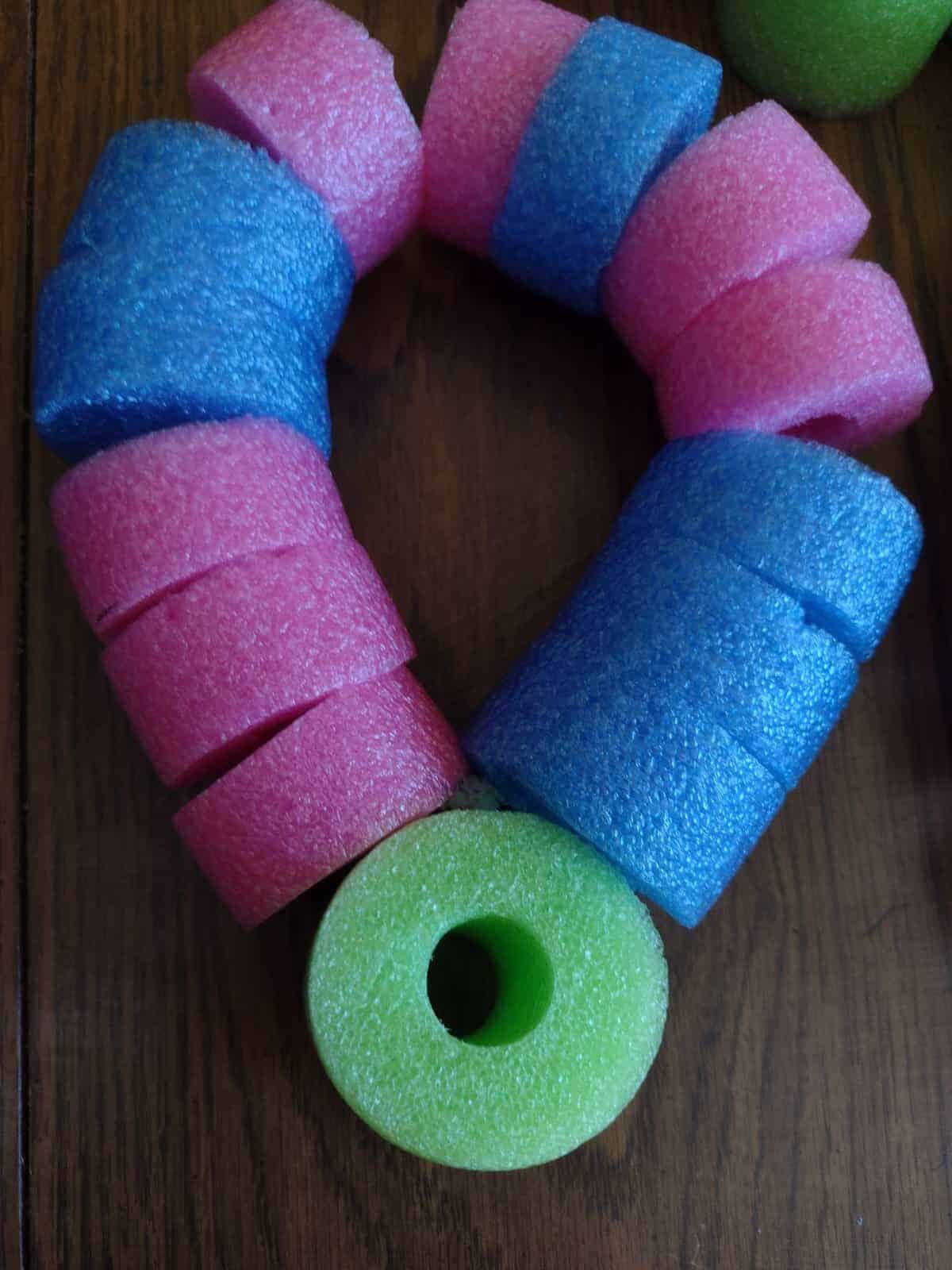Picture of a piece of a green pool noodle attached to the petal of a pool noodle craft