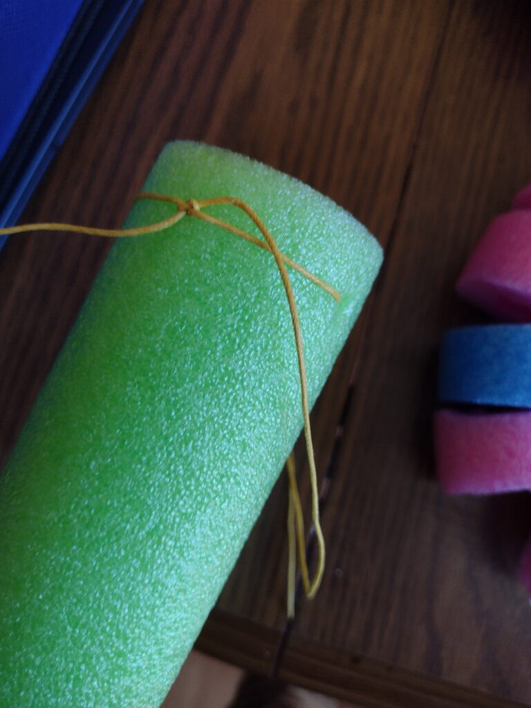Picture of bracelet cord threaded through a pool noodle and tied