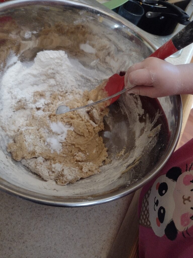 Picture of a preschooler dumping ingredients into cookie dough