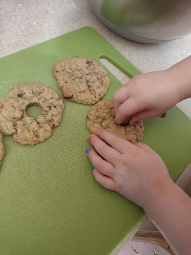 Picture of a preschooler stamping a circles out of cookies with a piping tip
