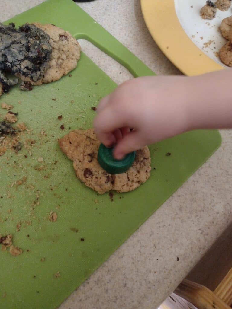 Picture of a preschooler stamping a circle out of the middle of an owl shaped cookie