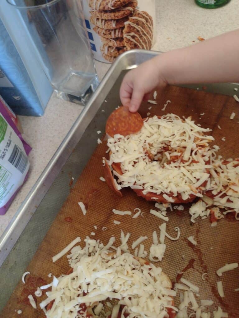 Picture of a preschooler putting a pepperoni ear on a P is for panda craft pizza