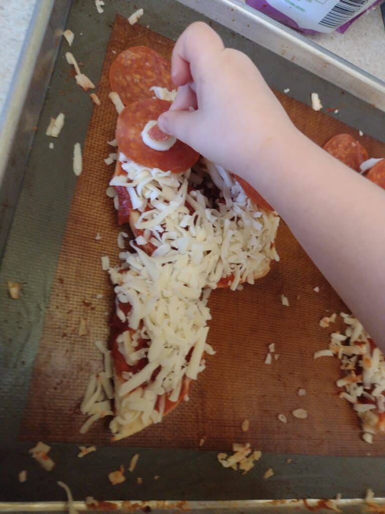 Picture of a preschooler putting the last piece of pepperoni on the eye of a P is for panda craft