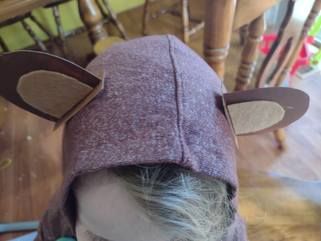 Picture of cardboard bear ears hot glued to the hood of a bear DIY costume