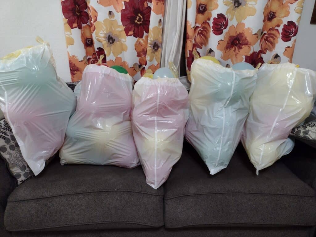 Picture of trash bags filled with balloons sitting on a couch