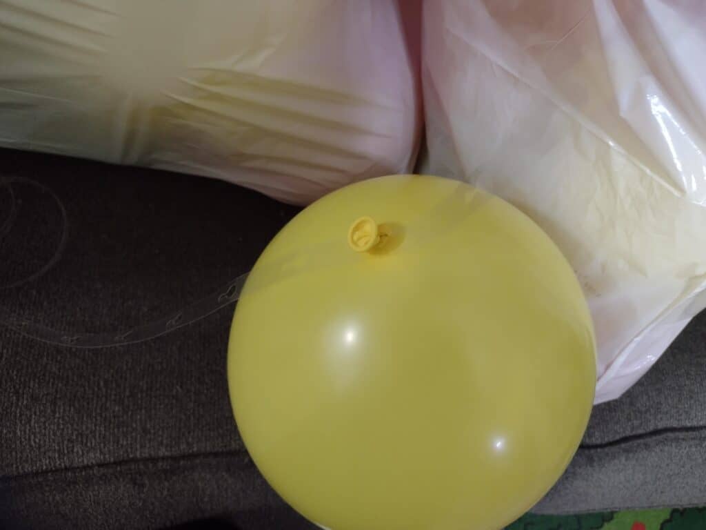 Picture showing how to make a balloon garland by threading the first balloon onto a strip of balloon tape