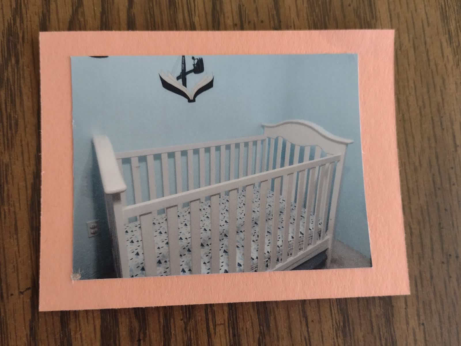 Picture of a printed picture of a crib glued to a piece of orange construction paper