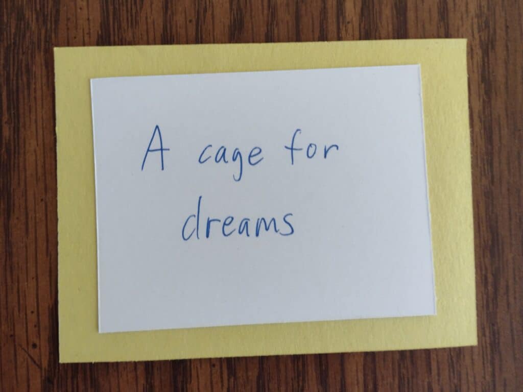 Picture of a clue "A cage for dreams" taped on one side to a piece of yellow construction paper