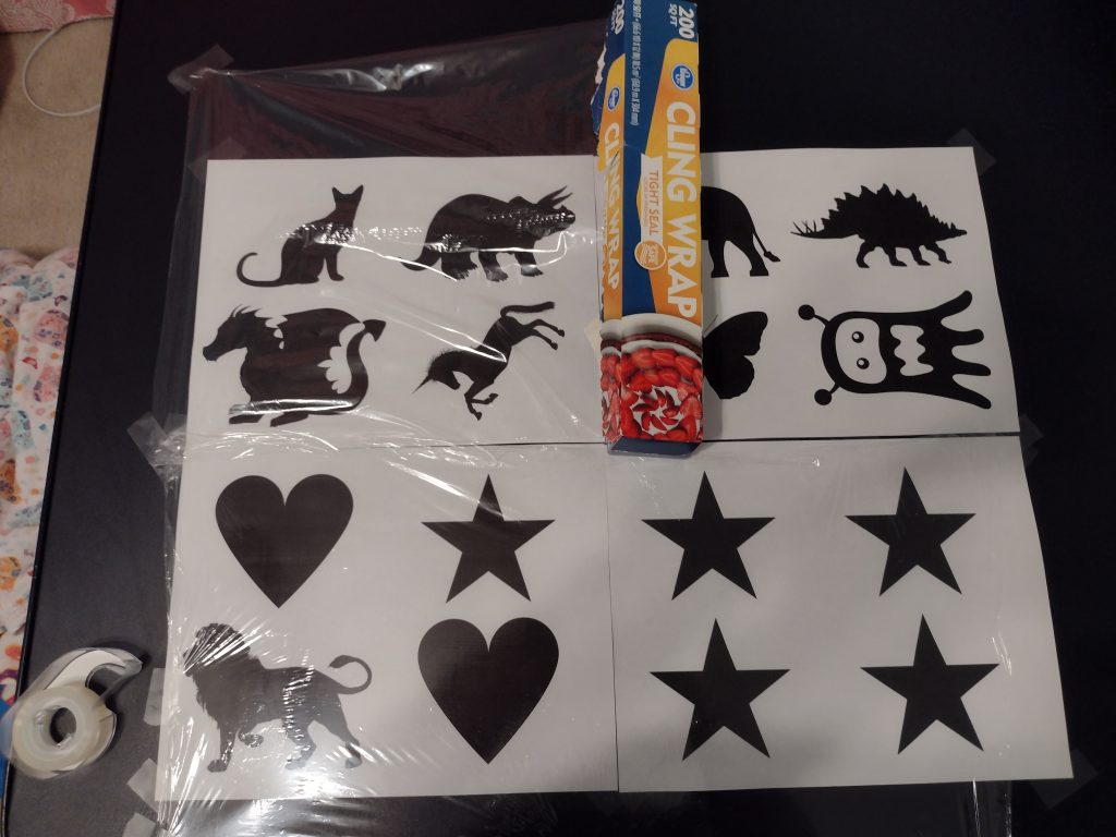 Picture of cling wrap taped to one side of a piece of paper and the box sitting halfway across the paper