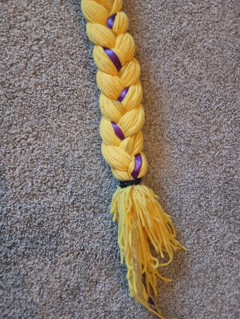 Picture of the end of a Rapunzel hair braid. A hair tie is glued in place and the ends are neat