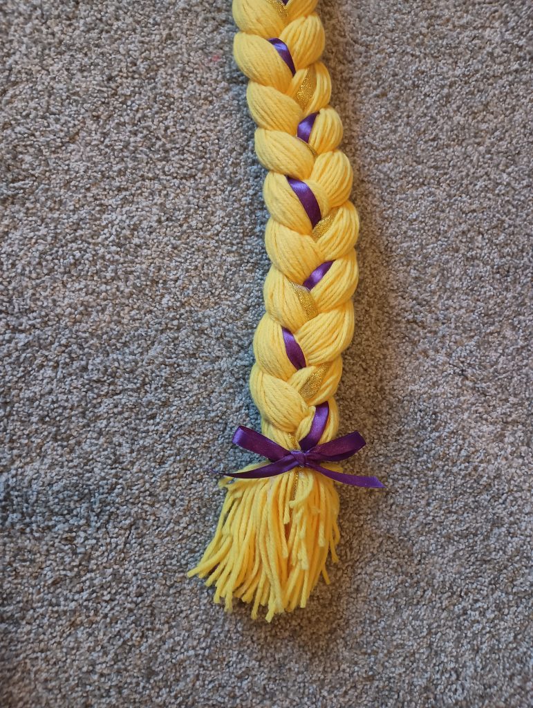 Picture of the end of a Rapunzel hair braid. There is a purple bow tied at the end and the ends are cut evenly