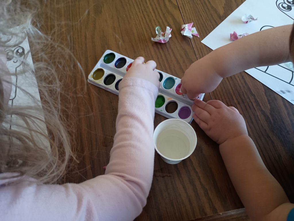 Picture of a toddler and a preschooler dipping wrapping paper into watercolors
