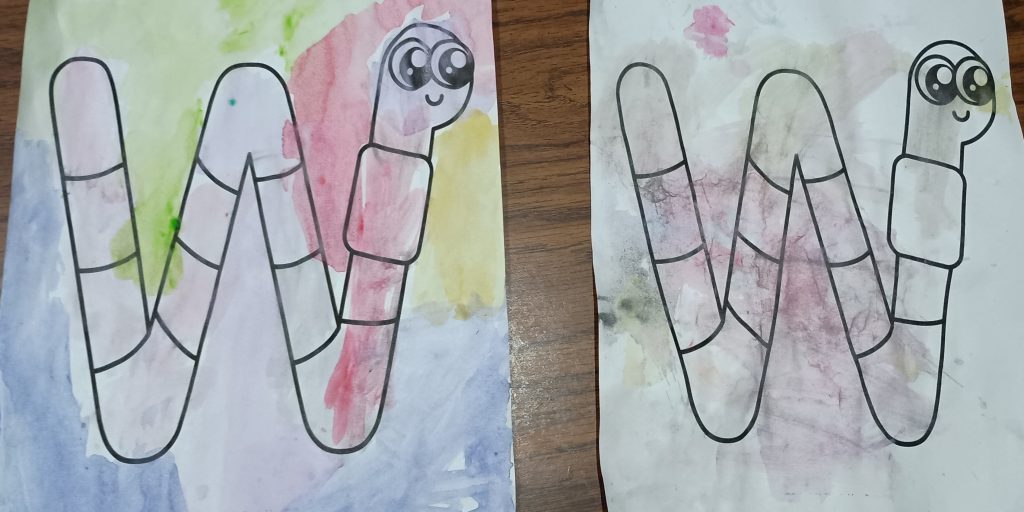 Picture of a W is for worm craft. There are two W shaped worm pictures painted by a toddler and a preschooler with watercolors and wrapping paper